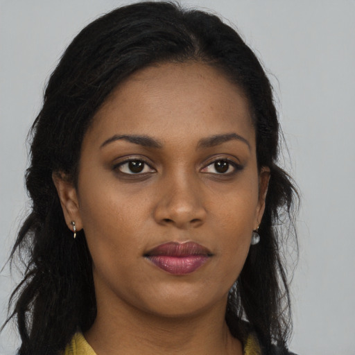 Joyful black young-adult female with long  brown hair and brown eyes