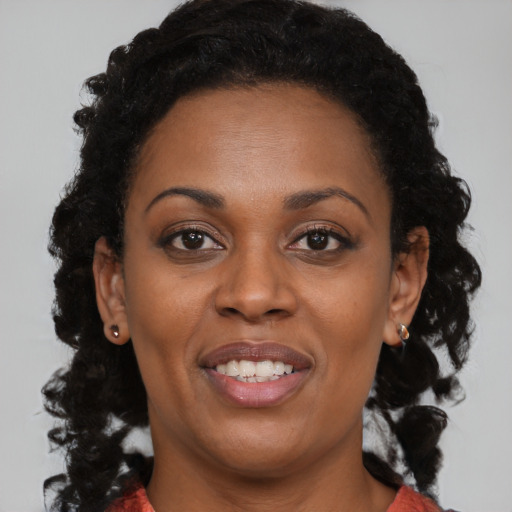 Joyful black adult female with long  brown hair and brown eyes