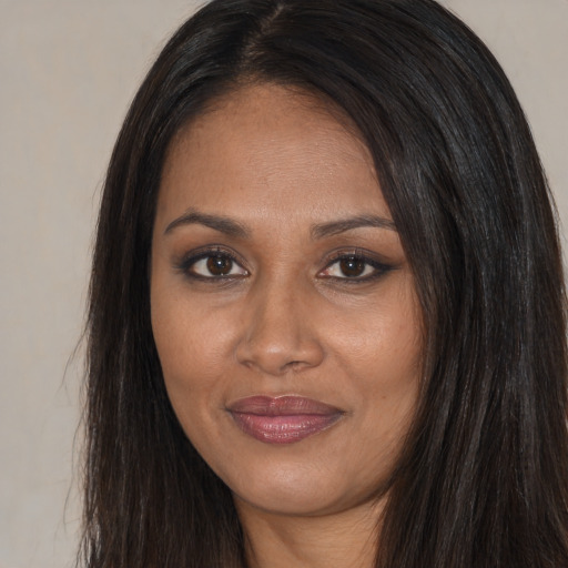 Joyful black young-adult female with long  brown hair and brown eyes