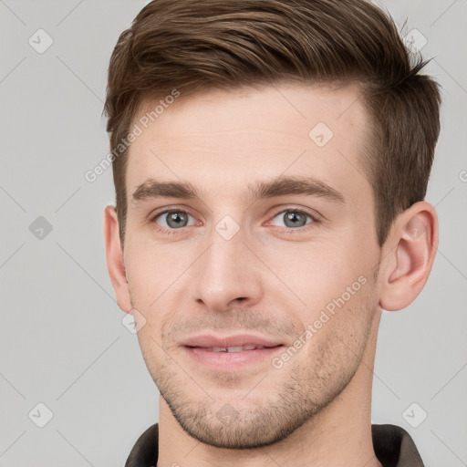 Joyful white young-adult male with short  brown hair and grey eyes