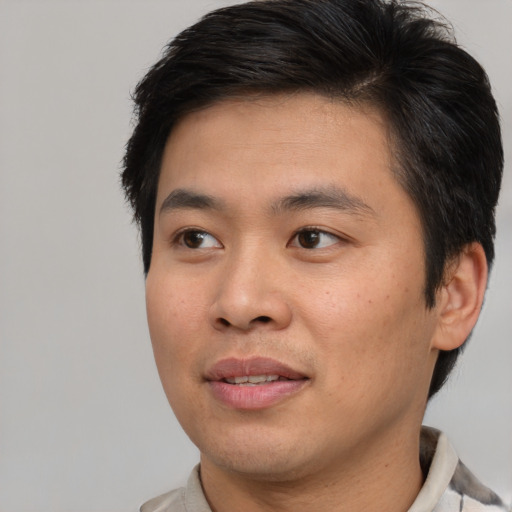 Joyful asian young-adult male with short  brown hair and brown eyes