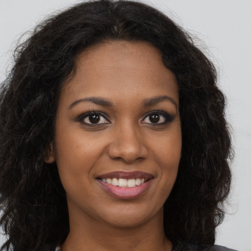 Joyful black young-adult female with long  brown hair and brown eyes