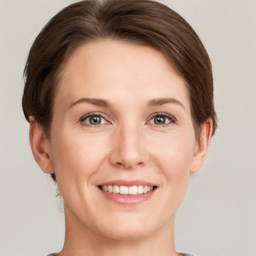 Joyful white young-adult female with short  brown hair and grey eyes