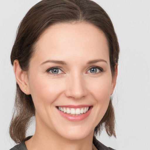 Joyful white young-adult female with medium  brown hair and grey eyes