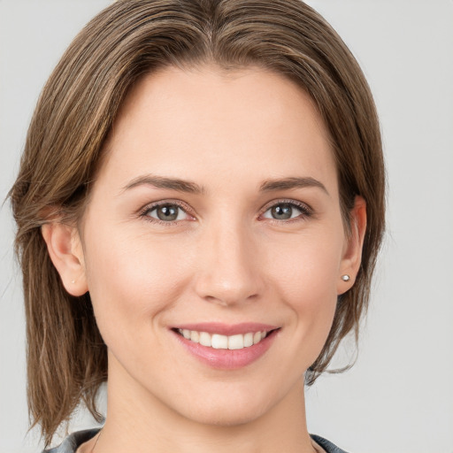 Joyful white young-adult female with medium  brown hair and grey eyes