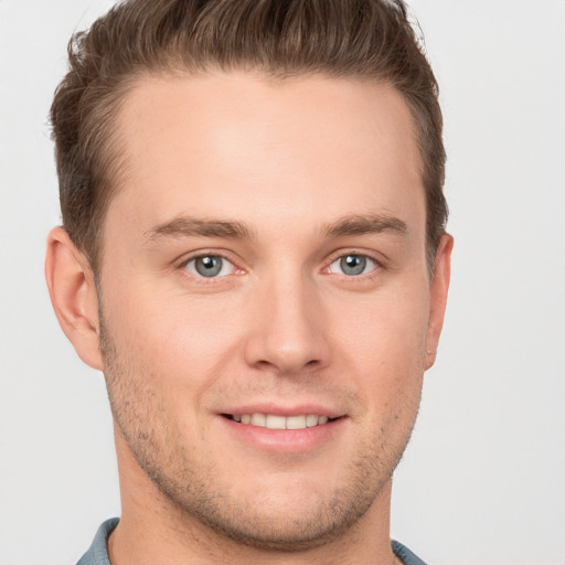 Joyful white young-adult male with short  brown hair and grey eyes