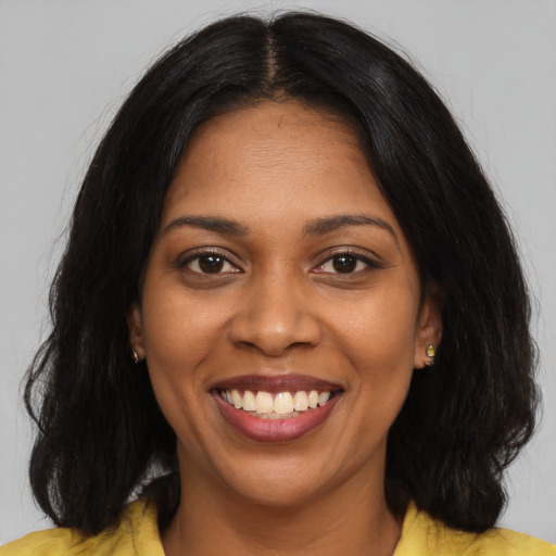 Joyful black young-adult female with long  black hair and brown eyes