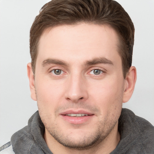 Joyful white young-adult male with short  brown hair and grey eyes