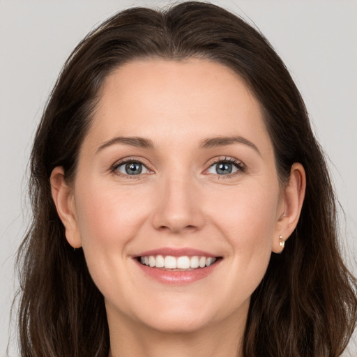 Joyful white young-adult female with long  brown hair and grey eyes