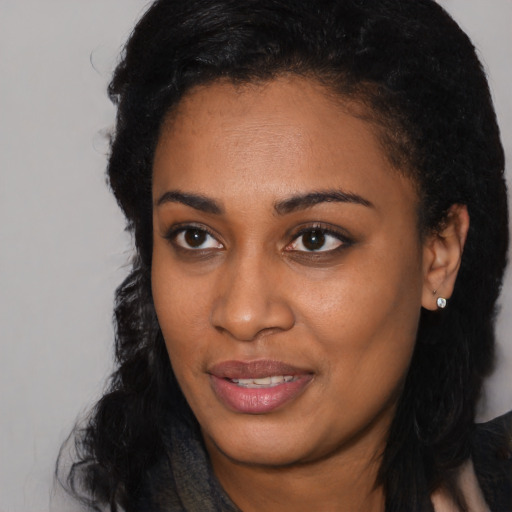 Joyful black young-adult female with long  black hair and brown eyes