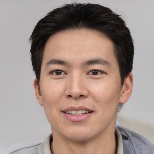 Joyful asian young-adult male with short  brown hair and brown eyes