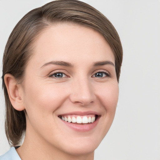 Joyful white young-adult female with medium  brown hair and grey eyes