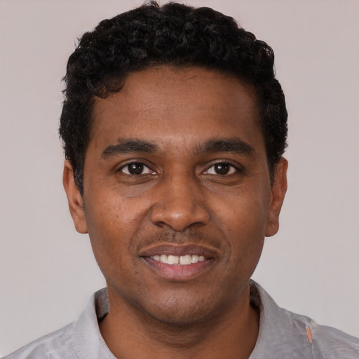 Joyful black young-adult male with short  black hair and brown eyes