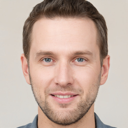 Joyful white young-adult male with short  brown hair and grey eyes