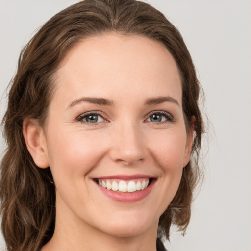 Joyful white young-adult female with medium  brown hair and grey eyes