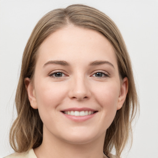 Joyful white young-adult female with medium  brown hair and grey eyes