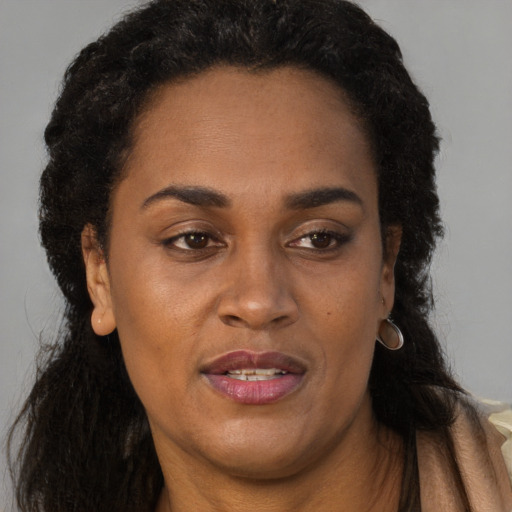 Joyful black adult female with long  brown hair and brown eyes