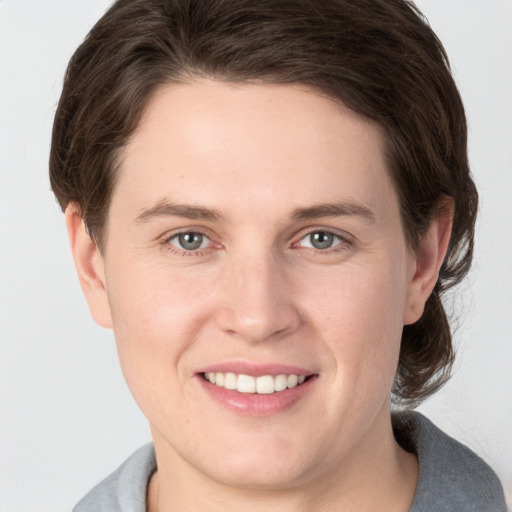 Joyful white young-adult male with medium  brown hair and grey eyes