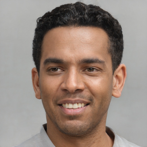 Joyful latino young-adult male with short  black hair and brown eyes