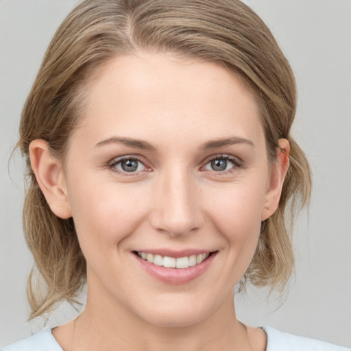 Joyful white young-adult female with medium  brown hair and grey eyes