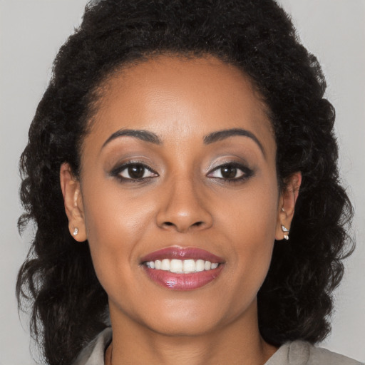 Joyful black young-adult female with long  brown hair and brown eyes