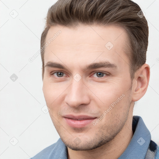 Joyful white young-adult male with short  brown hair and grey eyes