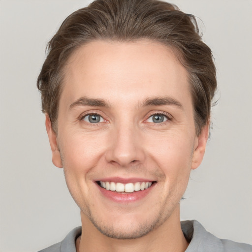 Joyful white young-adult male with short  brown hair and grey eyes