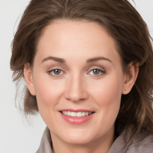 Joyful white young-adult female with medium  brown hair and grey eyes