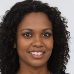 Joyful black young-adult female with long  brown hair and brown eyes