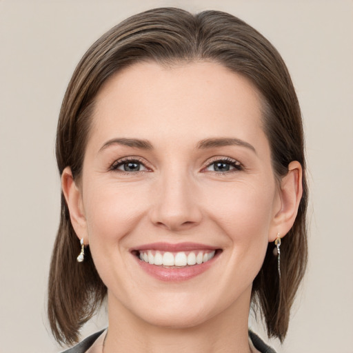 Joyful white young-adult female with medium  brown hair and grey eyes