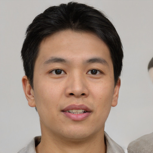 Joyful asian young-adult male with short  brown hair and brown eyes