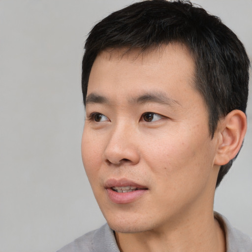 Joyful asian young-adult male with short  black hair and brown eyes