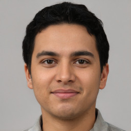 Joyful latino young-adult male with short  black hair and brown eyes