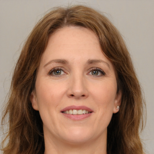 Joyful white adult female with long  brown hair and green eyes