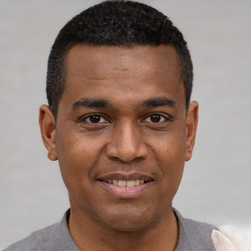 Joyful black young-adult male with short  black hair and brown eyes
