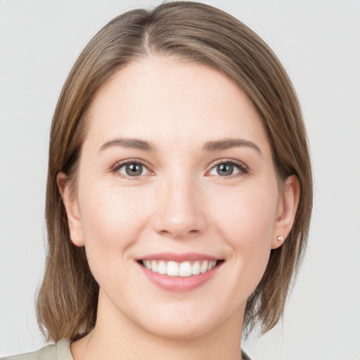 Joyful white young-adult female with medium  brown hair and grey eyes