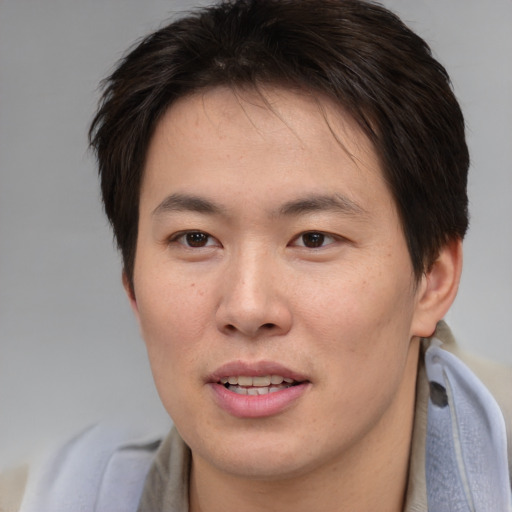 Joyful asian young-adult male with medium  brown hair and brown eyes