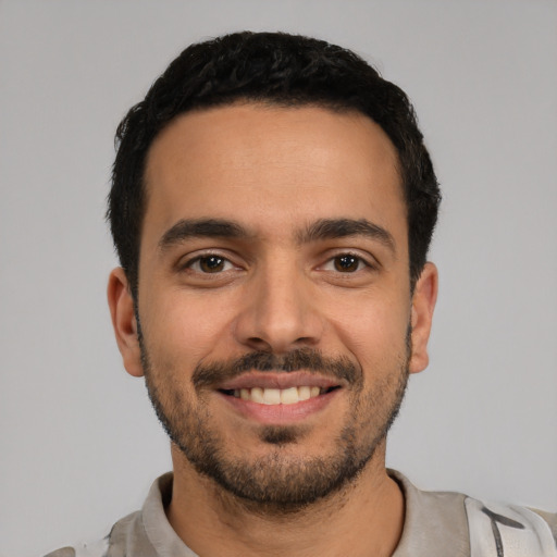 Joyful latino young-adult male with short  black hair and brown eyes