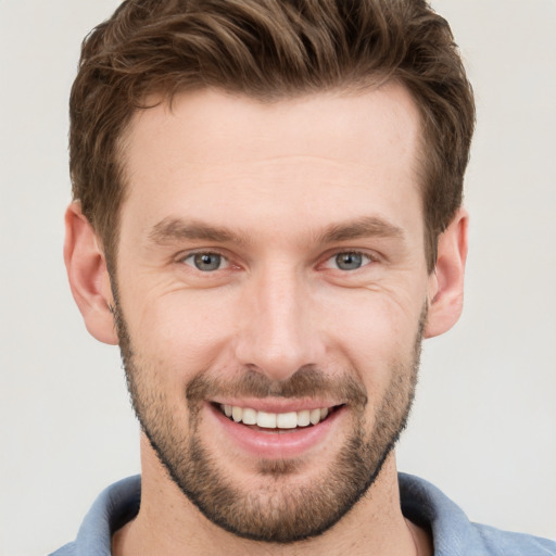 Joyful white young-adult male with short  brown hair and grey eyes