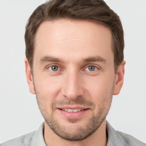 Joyful white young-adult male with short  brown hair and grey eyes