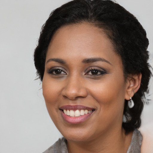 Joyful black young-adult female with long  black hair and brown eyes