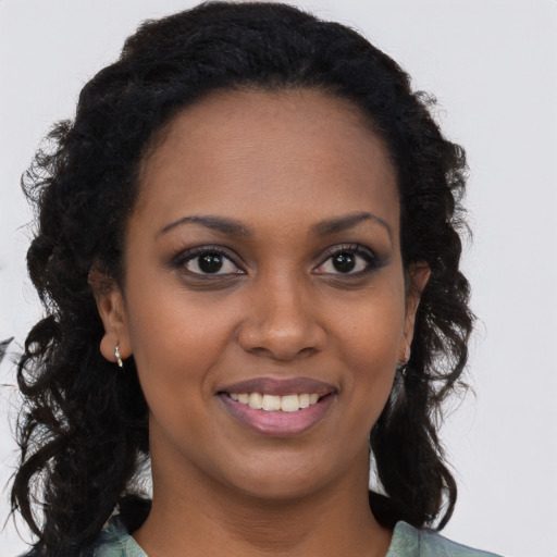 Joyful black young-adult female with long  brown hair and brown eyes