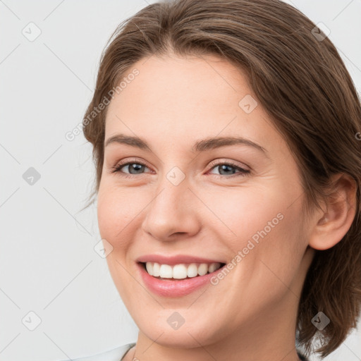 Joyful white young-adult female with medium  brown hair and grey eyes