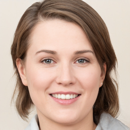 Joyful white young-adult female with medium  brown hair and grey eyes