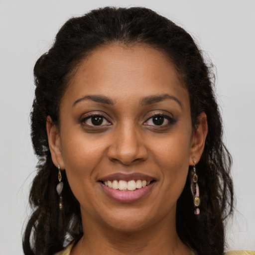 Joyful black young-adult female with long  brown hair and brown eyes