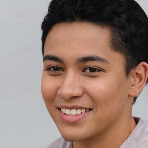 Joyful latino young-adult male with short  brown hair and brown eyes