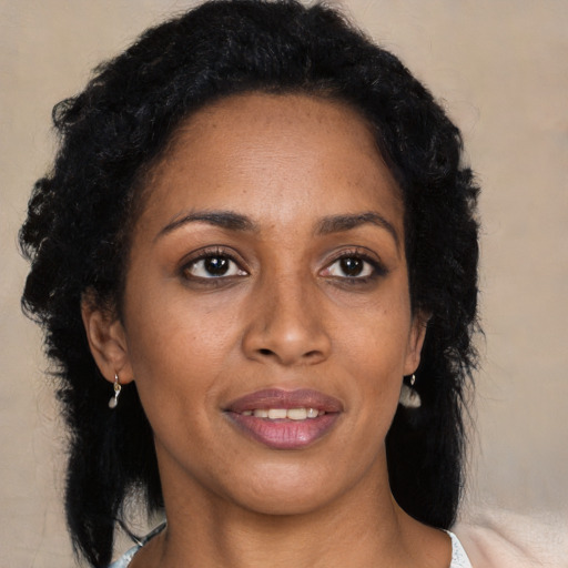 Joyful black young-adult female with long  black hair and brown eyes