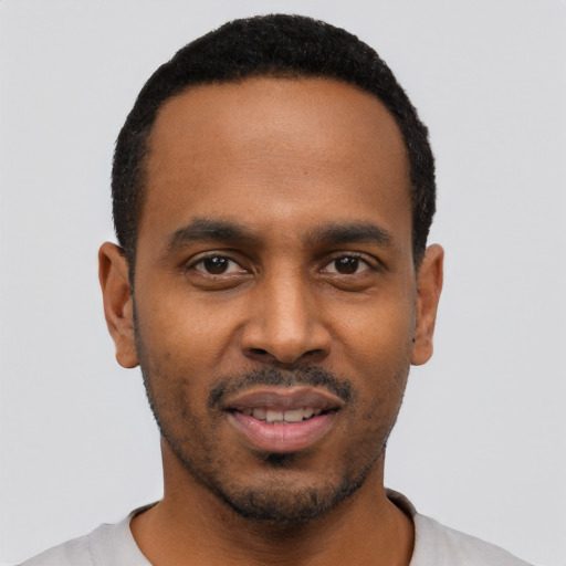 Joyful black young-adult male with short  black hair and brown eyes