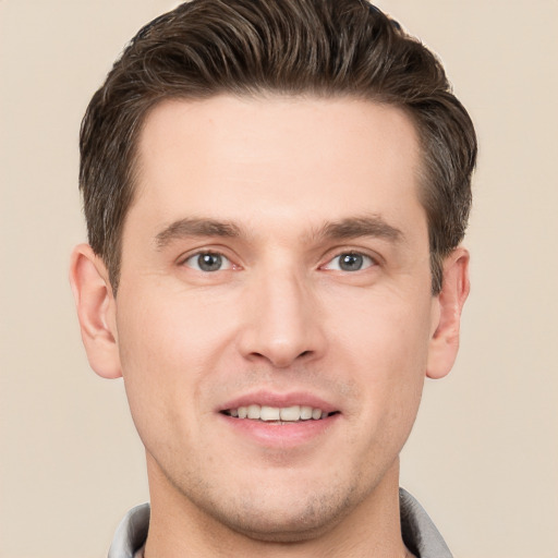 Joyful white young-adult male with short  brown hair and grey eyes