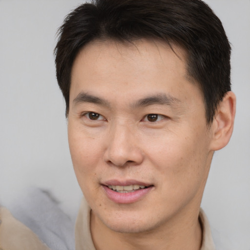 Joyful asian young-adult male with short  brown hair and brown eyes